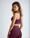 Woman wearing a burgundy sports bra and leggings with 'Miss Photogenic' branding on a grey background