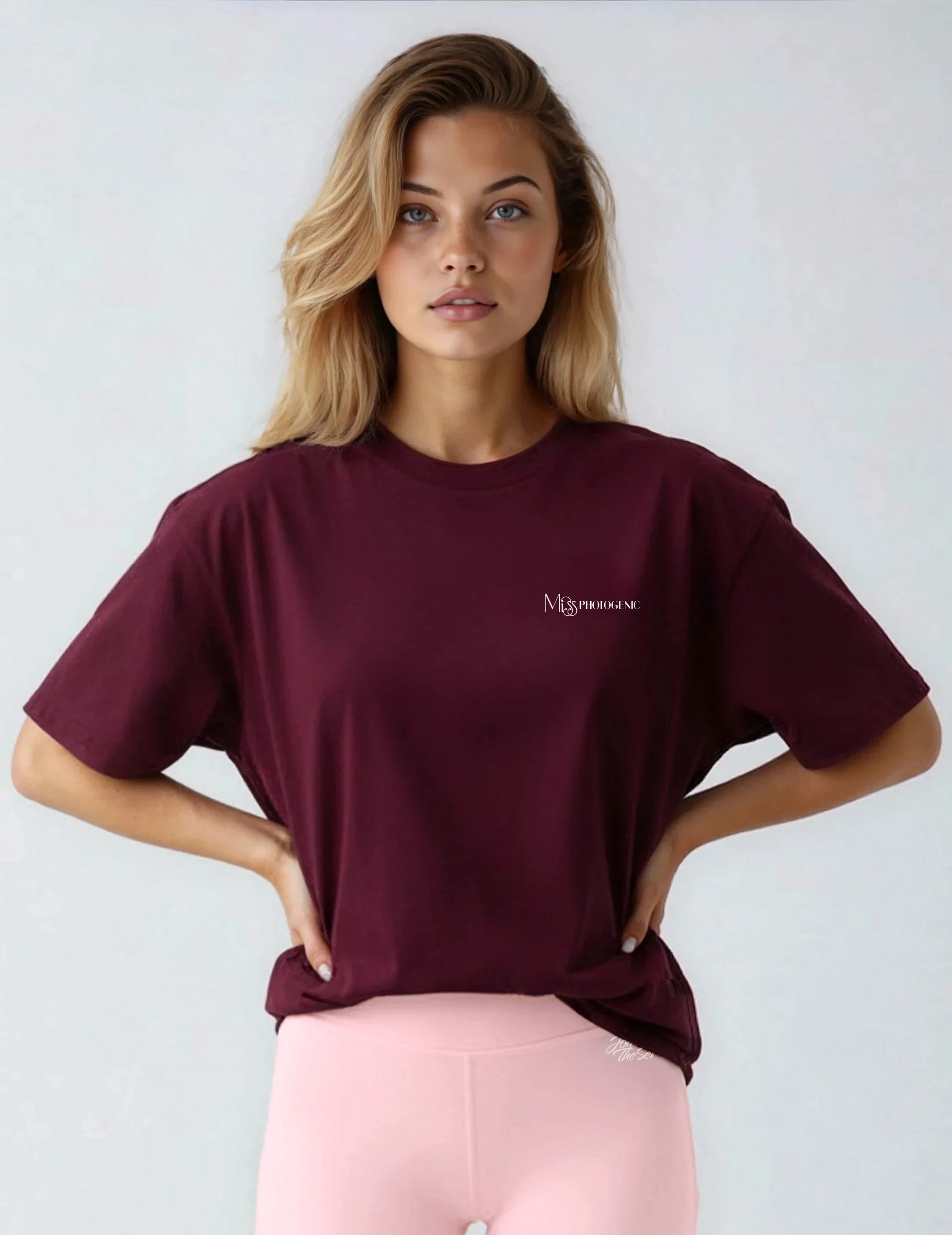 Woman wearing a burgundy t-shirt with a logo on a plain background